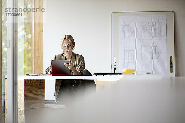 Geschäftsfrau lächelnd bei der Arbeit an einem digitalen Tablet zu Hause