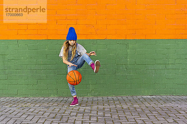 Junges Mädchen spielt Basketball  dribbelt und hebt das Bein