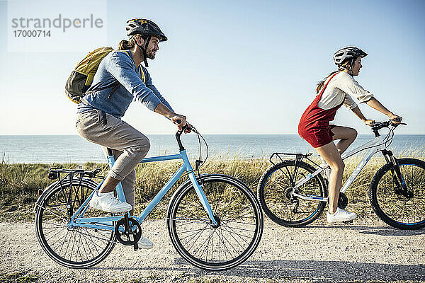 Pärchen mit Helm auf Fahrrädern gegen das Meer
