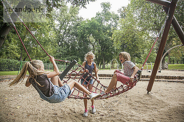 Junge und Mädchen haben Spaß beim Spielen auf der Seilschaukel auf dem Spielplatz