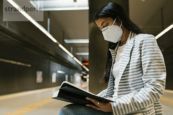 Frau liest ein Buch auf einer Bank in einer U-Bahn-Station während COVID-19