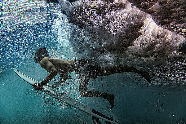 Unterwasseransicht eines männlichen Surfers beim Tauchen im Meer auf den Malediven