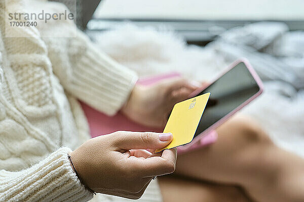 Frau kauft zu Hause mit Kreditkarte über das Mobiltelefon ein