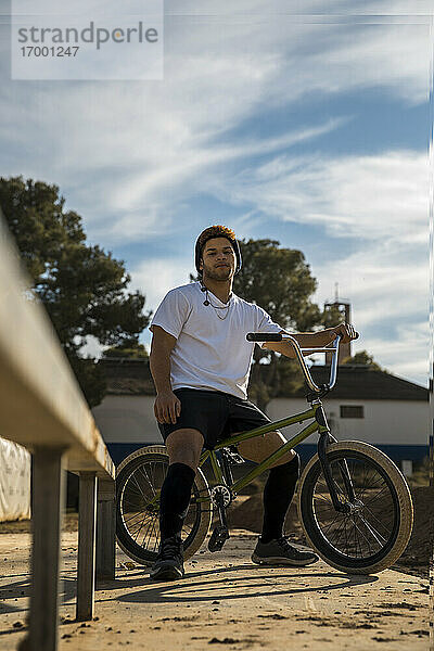 Selbstbewusster Mann mit Fahrrad am Fahrradteil gegen den Himmel