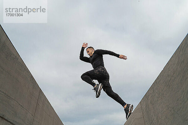 Sportler springt auf Wand gegen Himmel