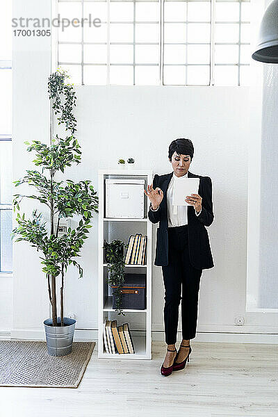 Geschäftsfrau stehend im Büro mit Dokumenten in der Hand