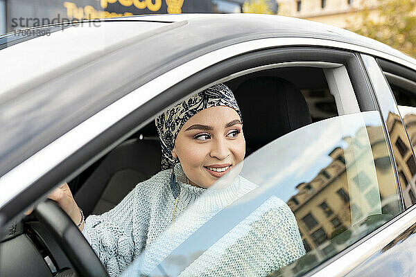 Lächelnde Frau  die wegschaut  während sie im Auto sitzt