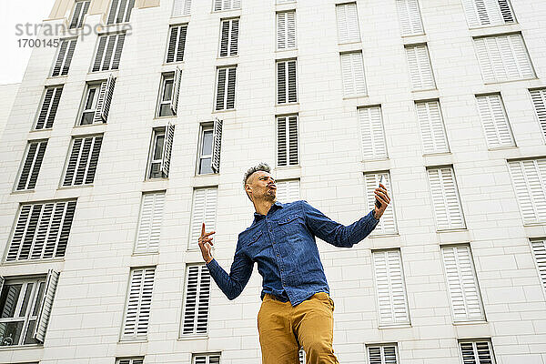 Mann tanzt gegen weißes Gebäude