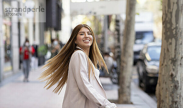 Lächelnde Frau  die sich auf einem Fußweg in der Stadt dreht
