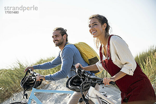 Paar mit Fahrrädern zu Fuß gegen den klaren Himmel