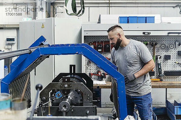 Männlicher Ingenieur betrachtet Maschinen in einer beleuchteten Industriefabrik
