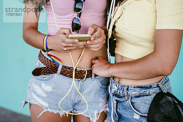 Nahaufnahme einer jungen Frau  die ein Smartphone benutzt  während sie mit ihrer Freundin in der Stadt steht