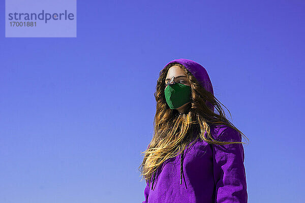 Teenager-Mädchen mit Kapuzenpulli und Gesichtsschutzmaske mit Fliegenaufkleber auf der Nase