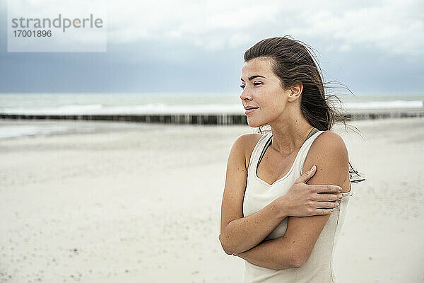 Junge Frau  die am Strand stehend die Aussicht betrachtet