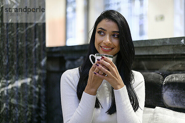 Schöne Geschäftsfrau hält Kaffeetasse  während sie in einem Café wegschaut