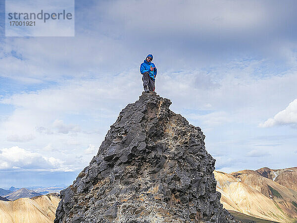 Wanderer posiert auf dem Gipfel eines Vulkanhügels in Landmannalaugar
