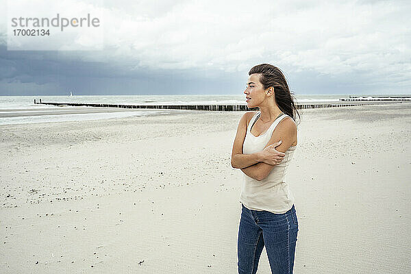Junge Frau  die am Strand stehend die Aussicht betrachtet