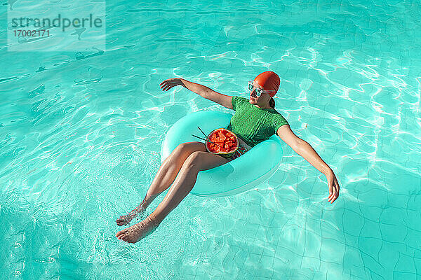 Frau mit Schwimmreifen und Wassermelone im Schwimmbad