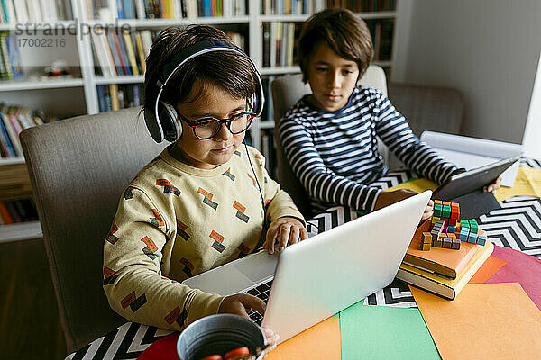 Junge zeigt Laptop an männlichen Freund auf Tisch zu Hause
