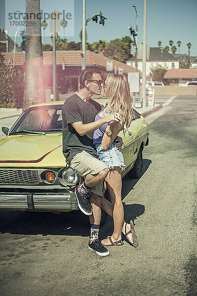 Junge Freundin und Freund umarmen sich  während sie neben einem Auto auf der Straße stehen