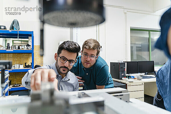 Geschäftsmann und männlicher Kollege bei der Prüfung einer Vermessungsmaschine in einer Produktionsstätte