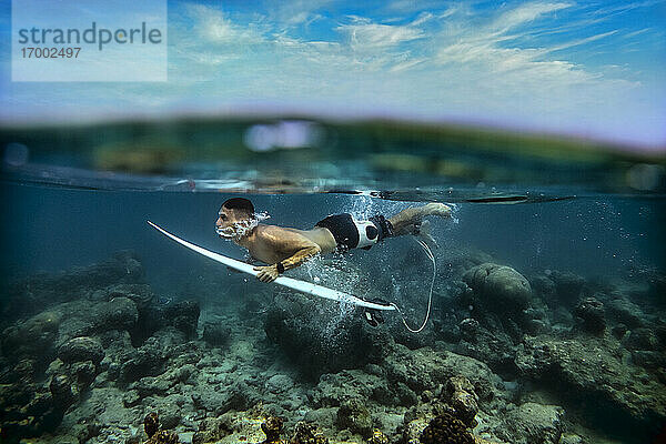Hemdloser männlicher Surfer beim Tauchen im Meer auf den Malediven