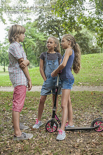 Mädchen im Gespräch mit einem Jungen  während sie im Herbst im Park stehen