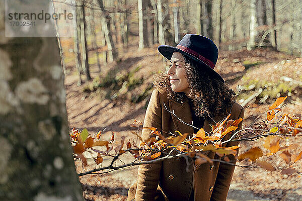 Ältere Frau lächelt  während sie sich im Wald umsieht
