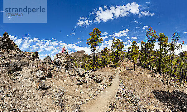 Mann auf einem Felsen sitzend beim Wandern im Teide-Nationalpark  Teneriffa  Kanarische Inseln  Spanien