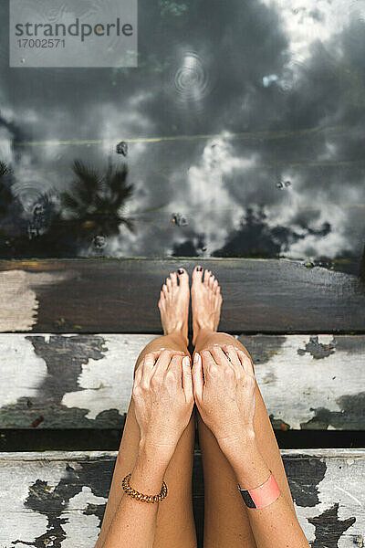 Nackte Beine einer Frau  die sich auf den Stufen einer unterirdischen Cenote entspannt