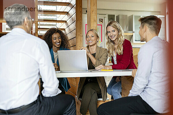Geschäftsleute  die lächelnd in einer Sitzung zusammenarbeiten  während sie im Büro sitzen