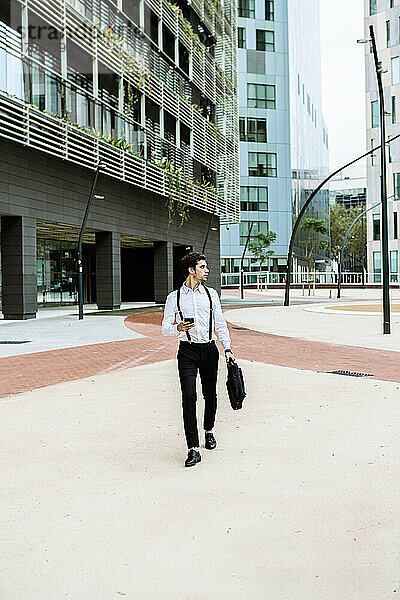 Stilvoller Geschäftsmann mit Smartphone beim Spaziergang in der Stadt