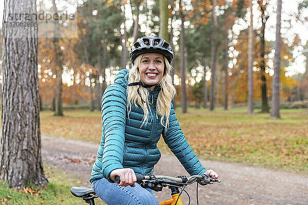 Lächelnde Frau  die ein Fahrrad hält  während sie in Cannock Chase steht