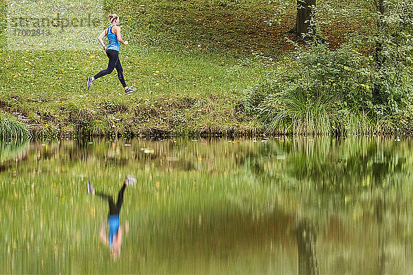 Reflexion einer jungen Sportlerin beim Joggen im Wald