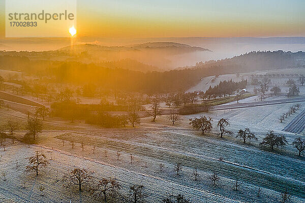 Deutschland  Baden-Württemberg  Berglen  Drohnenblick auf ländliche Felder bei nebligem Herbstsonnenaufgang