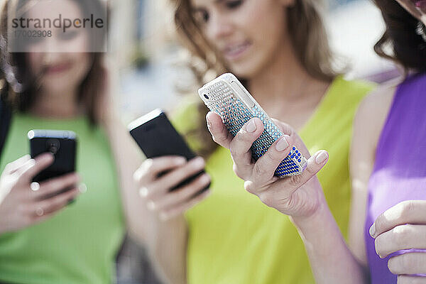 Weibliche Geschäftskollegen nutzen Mobiltelefone für Textnachrichten