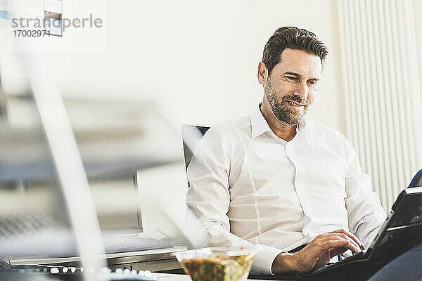 Geschäftsmann benutzt digitales Tablet während der Mittagspause im Büro