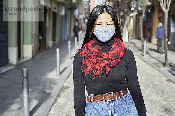 Junge Frau mit Gesichtsschutzmaske auf der Straße in der Stadt