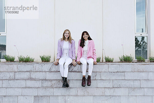 Glückliche Schwestern sitzen auf einer Stützmauer