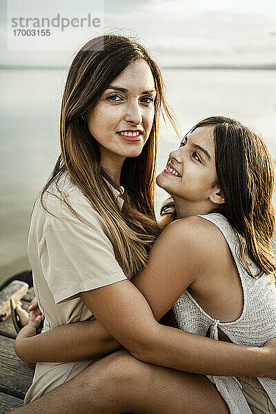 Mutter und Tochter umarmen sich am Steg am See