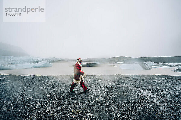 Island  Weihnachtsmann geht in Gletscherlandschaft