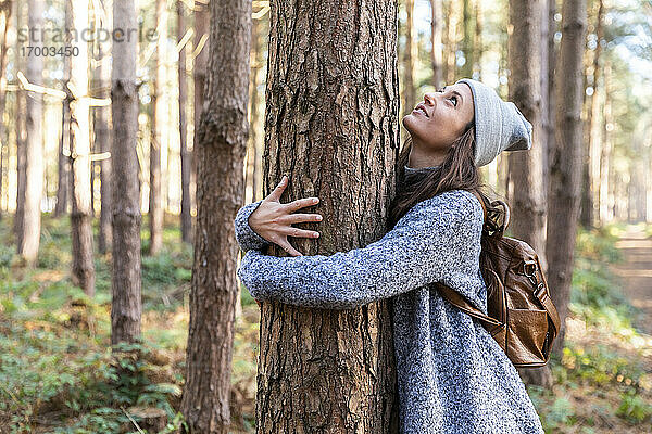 Wanderin umarmt Baumstamm bei Erkundungstour im Waldgebiet Cannock Chase