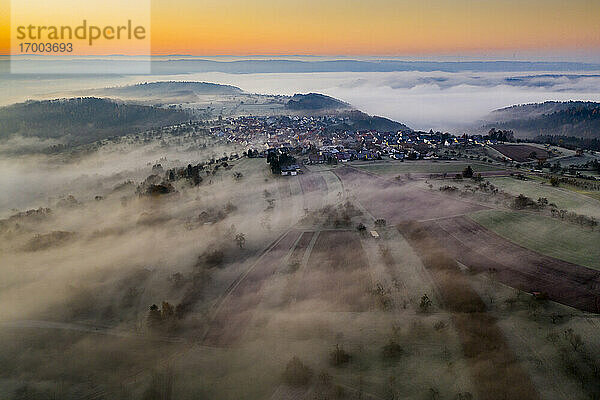 Deutschland  Baden-Württemberg  Berglen  Drohnenansicht eines in dichten Nebel gehüllten Dorfes in der Morgendämmerung