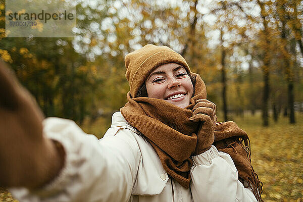 Glückliche junge Frau nimmt Selfie im Herbst Park