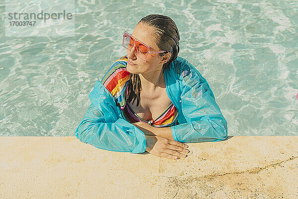 Porträt einer gekleideten Frau  die sich im Schwimmbad entspannt