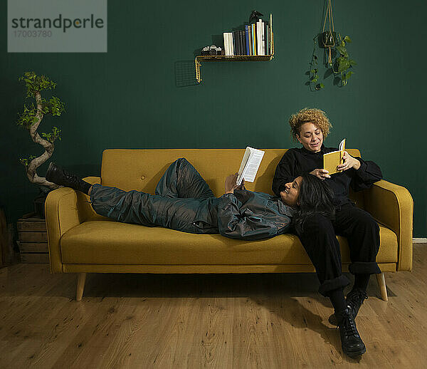 Lesbisches Paar liest Bücher auf dem Sofa