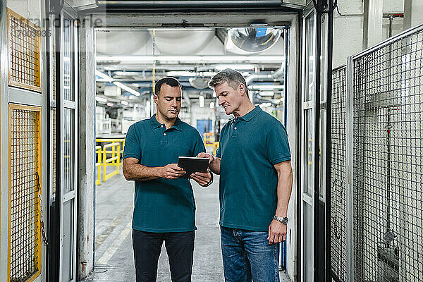 Männliche Ingenieure diskutieren in der Fabrik über ein digitales Tablet