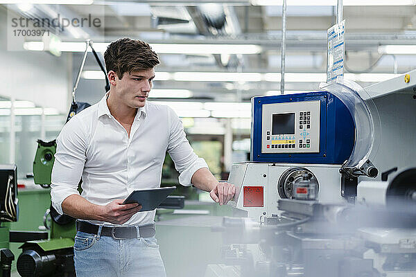 Männlicher Ingenieur  der in einer Fabrik mit einem digitalen Tablet Produktionsanlagen überprüft
