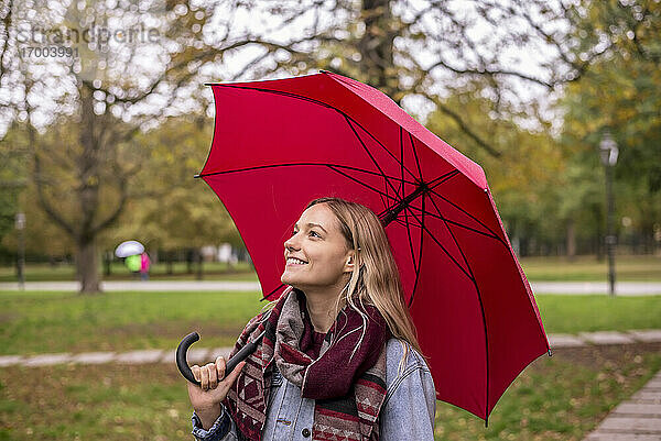 Nachdenkliche Frau mit Regenschirm in einem herbstlichen Park