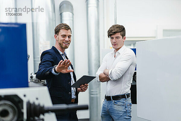 Lächelnder Geschäftsmann mit männlichem Ingenieur  der über Produktionsanlagen in der Industrie diskutiert